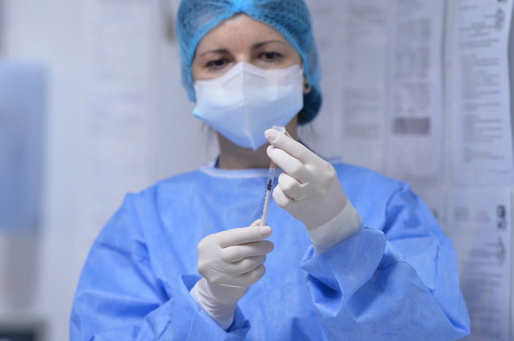 Asistentă care pregătește o doză de vaccin.