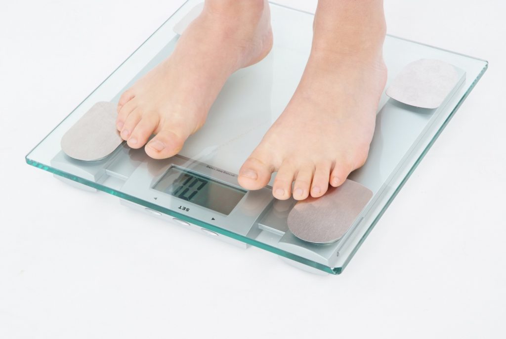 Femeie care stă pe cântar.