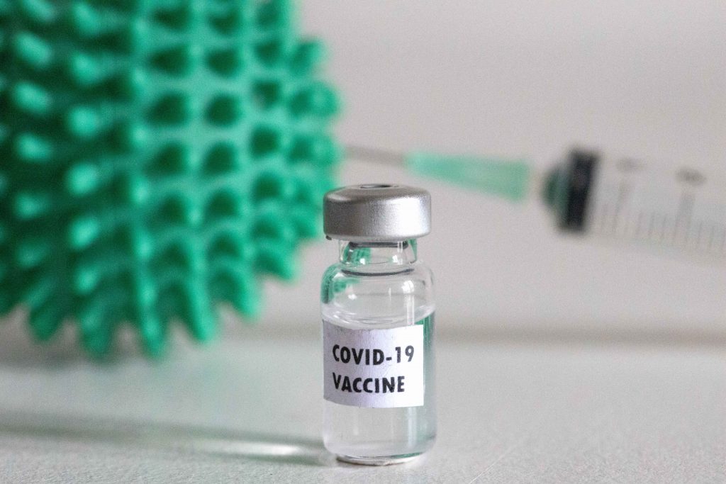 Vaccin anti-COVID cu seringă și virus ilustrate pe o masă.