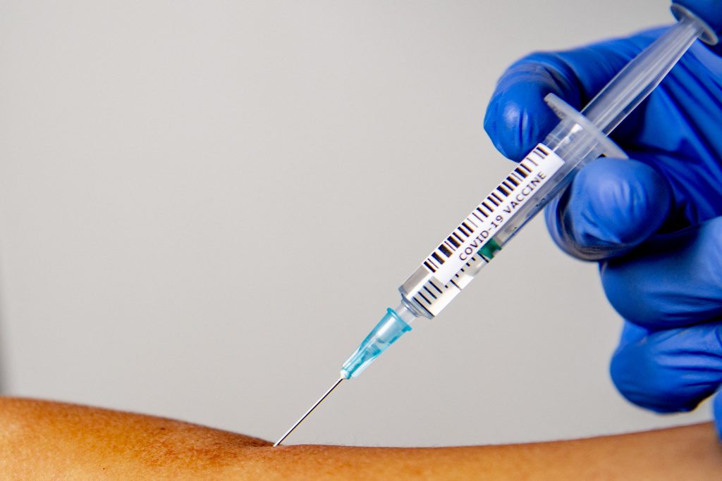 Asistentă care vaccinează o persoană.