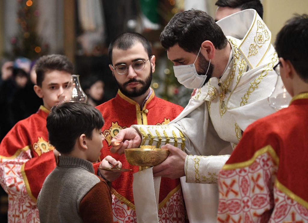 6427235 24.12.2020 A Catholic priest gives communion to a worshipper during a Catholic Christmas eve mass at the Cathedral of the Immaculate Conception, in Moscow, Russia.,Image: 578538193, License: Rights-managed, Restrictions: , Model Release: no
