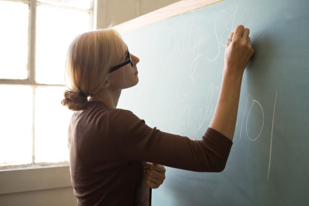 Profesoară care scrie cu creta pe tablă